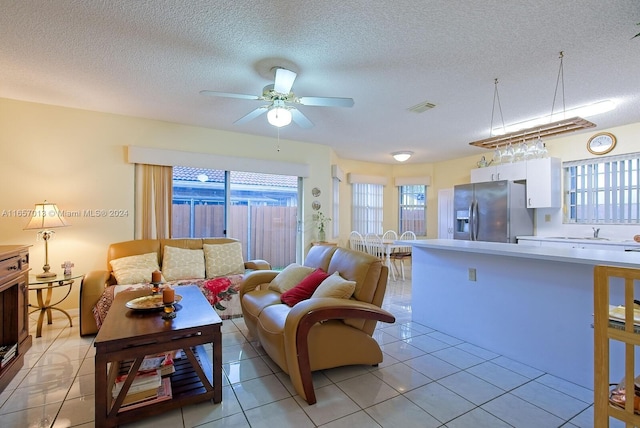 living room featuring ceiling fan, sink, light tile patterned flooring, and a textured ceiling