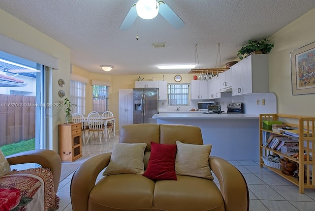 living room with a textured ceiling, light tile patterned floors, and ceiling fan