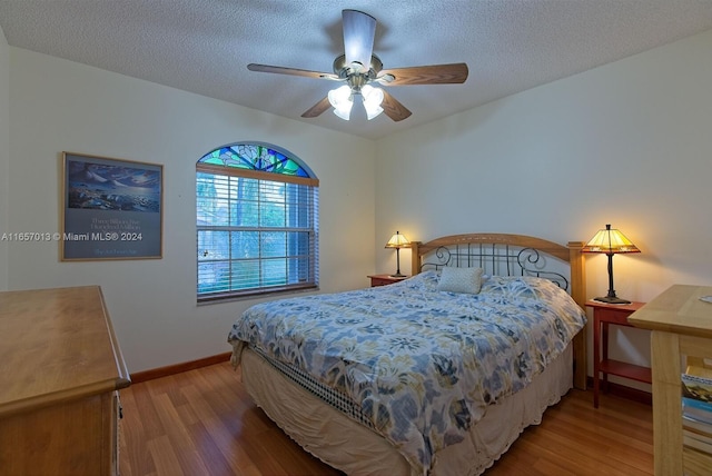 bedroom featuring baseboards, a ceiling fan, wood finished floors, and a textured ceiling
