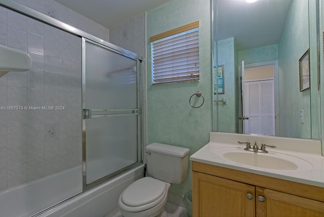 bathroom featuring bath / shower combo with glass door, toilet, and vanity