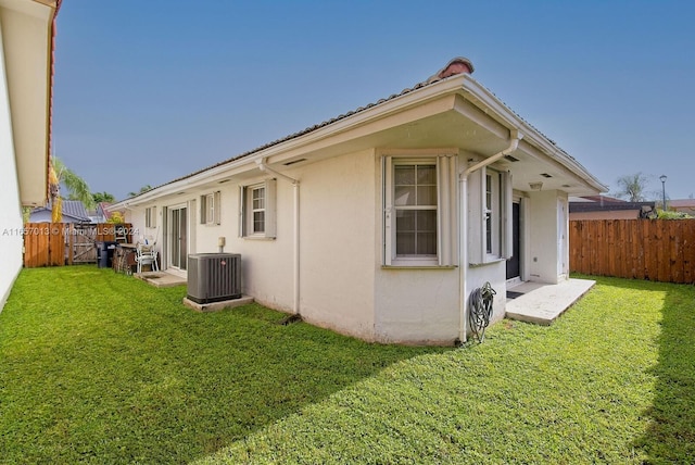exterior space with cooling unit, a fenced backyard, stucco siding, and a yard