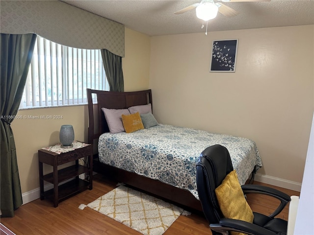 bedroom featuring ceiling fan, hardwood / wood-style flooring, and a textured ceiling