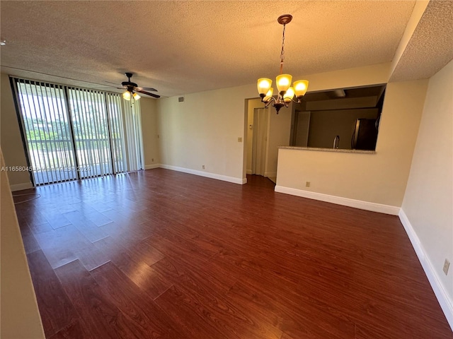 unfurnished room featuring expansive windows, a textured ceiling, ceiling fan with notable chandelier, and dark hardwood / wood-style flooring