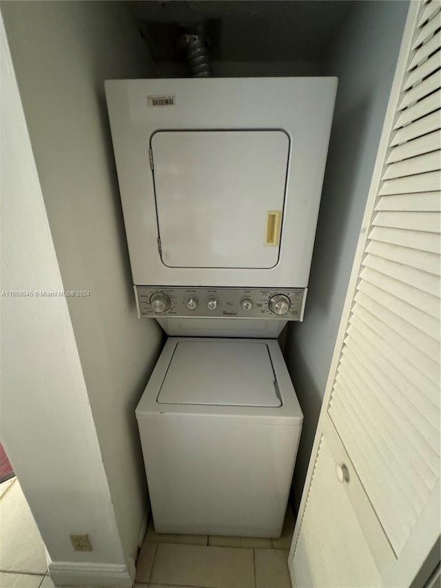 clothes washing area featuring light tile patterned floors and stacked washer and clothes dryer