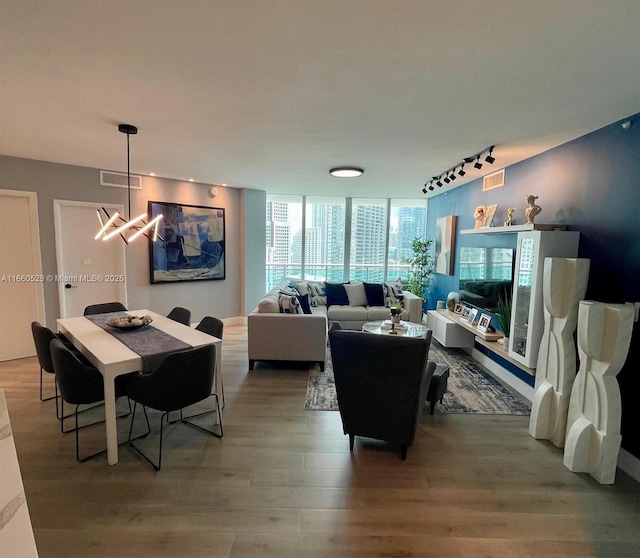 living area with an inviting chandelier, wood finished floors, visible vents, and rail lighting