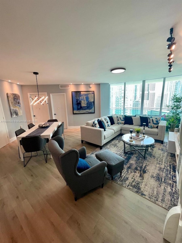 living room featuring a wall of windows, visible vents, and wood finished floors