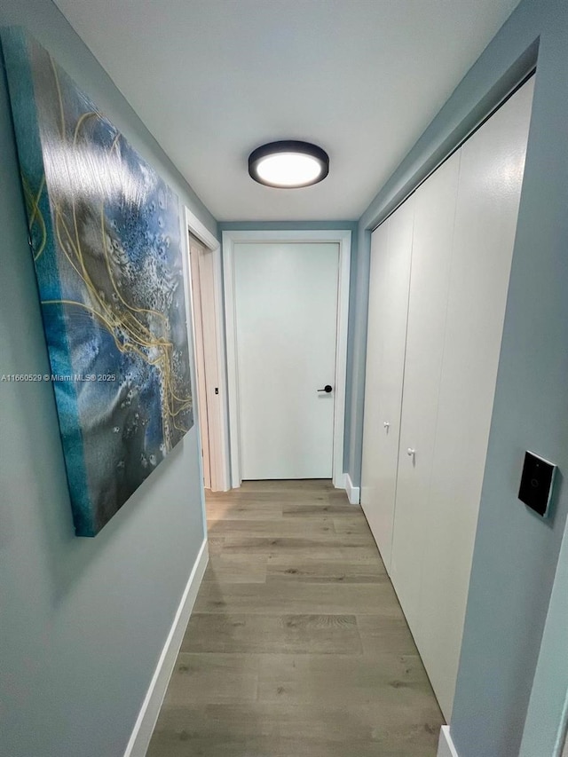 corridor featuring light wood-style floors and baseboards