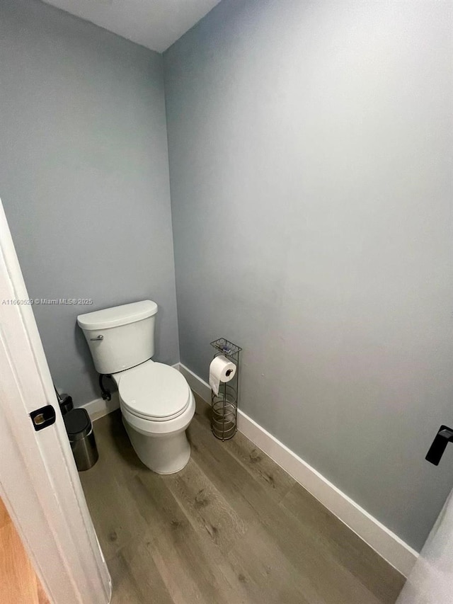 bathroom with baseboards, toilet, and wood finished floors