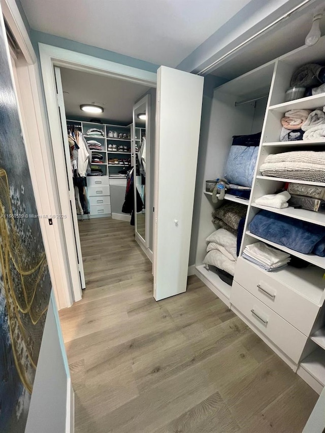 walk in closet with wood finished floors