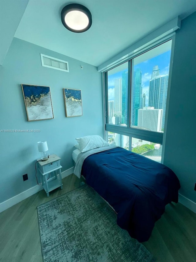 bedroom with a view of city, visible vents, baseboards, and wood finished floors