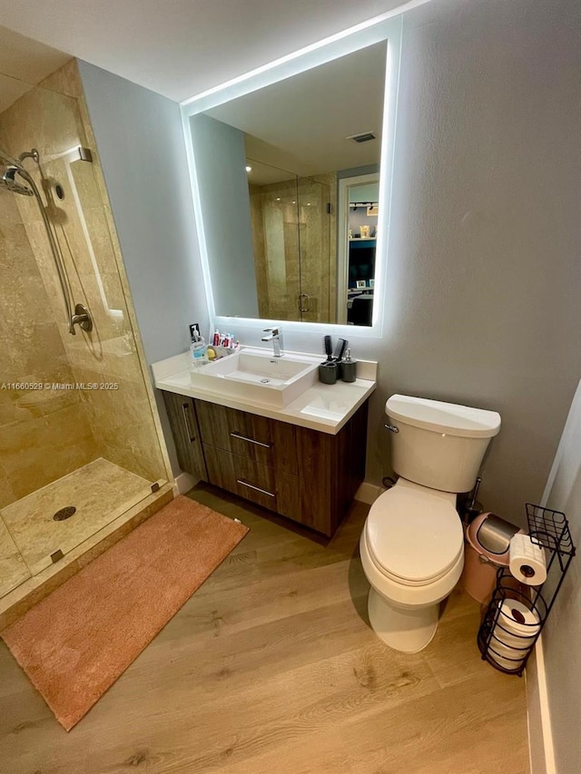 full bathroom with toilet, wood finished floors, vanity, visible vents, and a stall shower