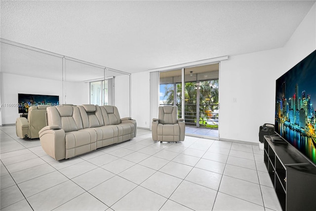 living room featuring light tile patterned floors, a textured ceiling, and a wall of windows