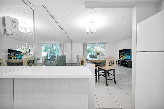 kitchen with a notable chandelier, white refrigerator, a textured ceiling, decorative light fixtures, and light tile patterned floors