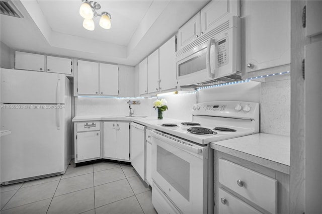 kitchen with tasteful backsplash, white appliances, a raised ceiling, white cabinetry, and light tile patterned flooring