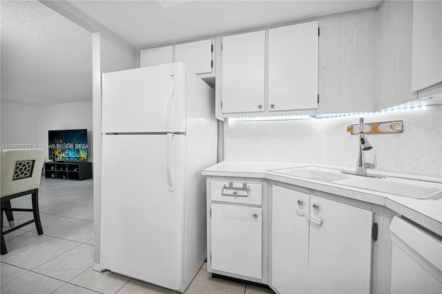 kitchen featuring white appliances, white cabinets, sink, light tile patterned floors, and a textured ceiling