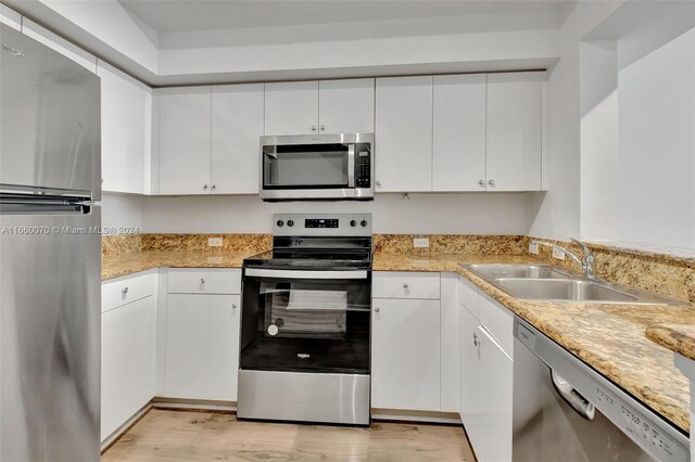 kitchen with appliances with stainless steel finishes, sink, and white cabinetry