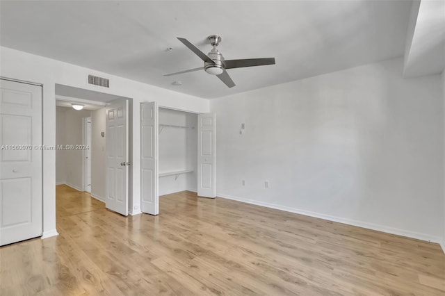 unfurnished bedroom with light hardwood / wood-style floors, ceiling fan, and multiple closets