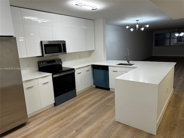 kitchen featuring kitchen peninsula, appliances with stainless steel finishes, an inviting chandelier, white cabinets, and light hardwood / wood-style floors