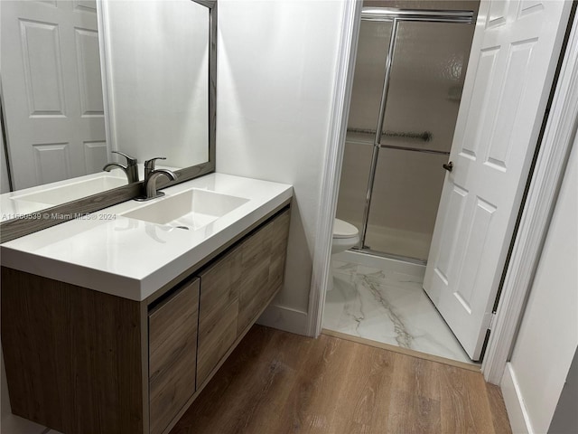 bathroom with toilet, vanity, a shower with shower door, and hardwood / wood-style flooring