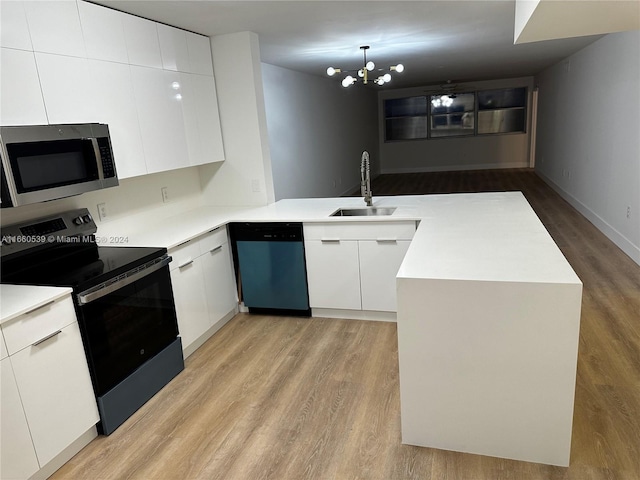 kitchen featuring sink, an inviting chandelier, appliances with stainless steel finishes, white cabinets, and light wood-type flooring