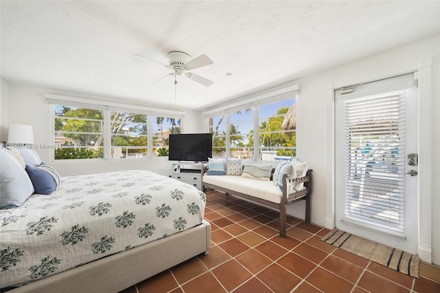 bedroom with multiple windows, access to outside, ceiling fan, and dark tile patterned floors