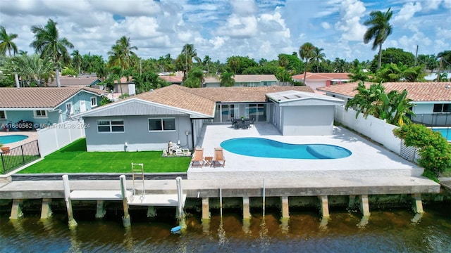 rear view of house with a fenced in pool, a water view, a lawn, and a patio