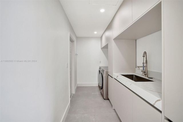 laundry room with cabinets, independent washer and dryer, and sink