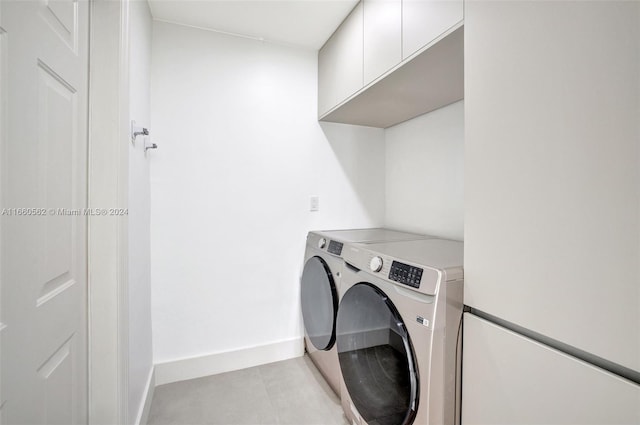 clothes washing area featuring light tile patterned flooring, cabinets, and separate washer and dryer