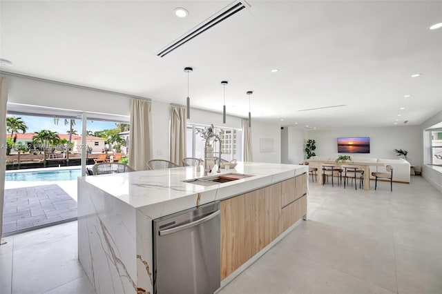 kitchen with decorative light fixtures, light stone countertops, a center island with sink, stainless steel dishwasher, and sink