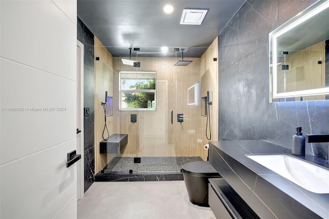 bathroom with a shower with door, vanity, toilet, and tile walls