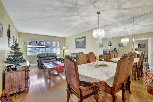 dining room with an inviting chandelier, a textured ceiling, and light hardwood / wood-style flooring