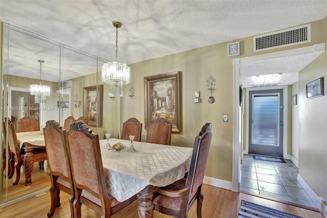 dining room featuring a textured ceiling, an inviting chandelier, and hardwood / wood-style floors