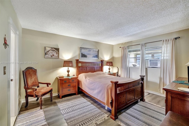 bedroom featuring a textured ceiling, cooling unit, and light wood-type flooring