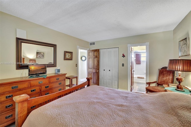 bedroom with a textured ceiling, ensuite bath, and a closet