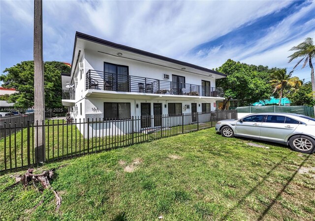 view of front of house featuring a balcony and a front lawn