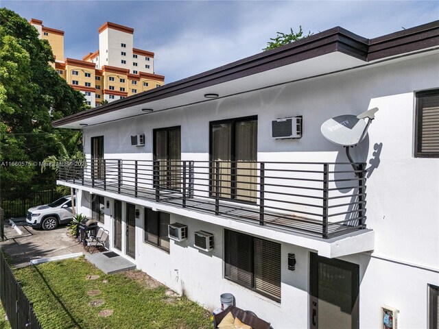 view of side of property with a balcony and a wall mounted air conditioner