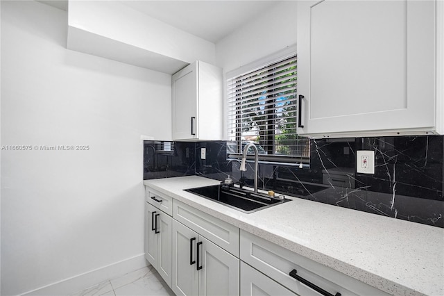 kitchen featuring light stone countertops, sink, and white cabinets