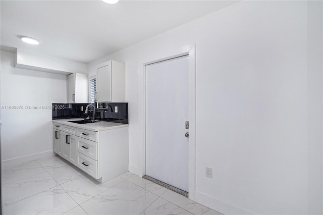 kitchen featuring white cabinetry, sink, and backsplash