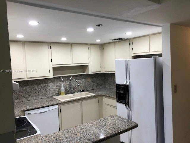 kitchen with dark stone countertops, sink, white appliances, and tasteful backsplash