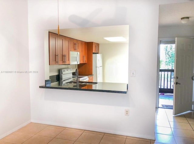 kitchen with light tile patterned floors, sink, kitchen peninsula, and white appliances