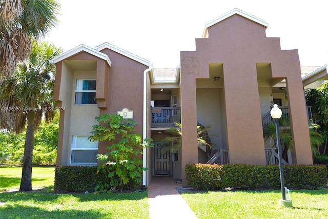 view of front of home featuring a balcony and a front lawn