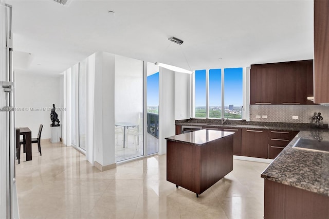 kitchen featuring decorative backsplash, a kitchen island, expansive windows, dark brown cabinetry, and sink