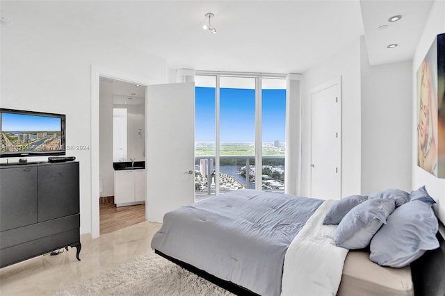 bedroom with light wood-type flooring, access to outside, floor to ceiling windows, and sink