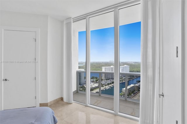 bedroom featuring expansive windows, access to exterior, and a water view