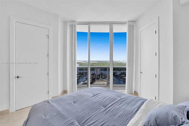 bedroom with light tile patterned floors, a wall of windows, and access to exterior