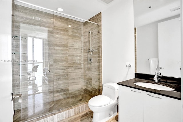 bathroom with a shower with shower door, vanity, and toilet