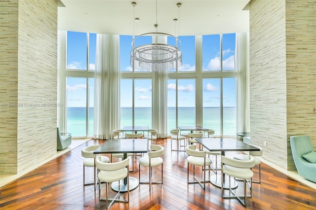 dining area featuring dark hardwood / wood-style floors, a high ceiling, and a water view