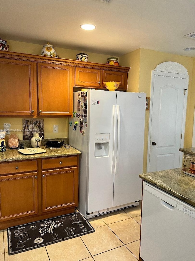 kitchen featuring stone counters, light tile patterned floors, and white appliances