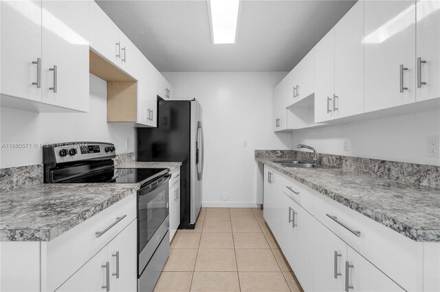 kitchen with sink, appliances with stainless steel finishes, light tile patterned floors, and white cabinetry