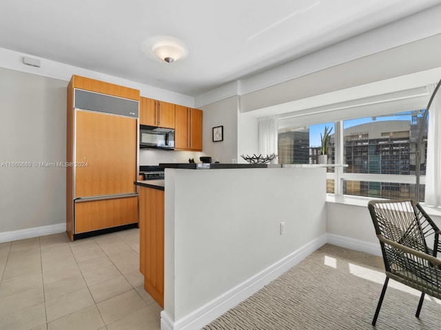 kitchen featuring light tile patterned floors, paneled fridge, and kitchen peninsula